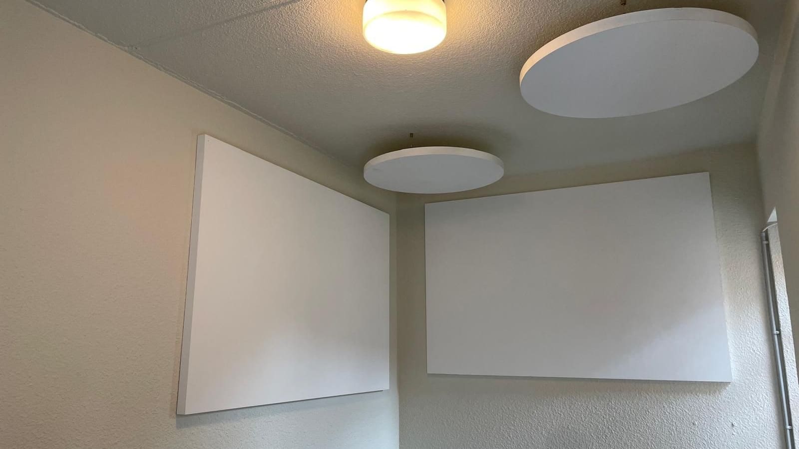 Panneaux absorbants acoustiques posés en mural et en plafond dans une pièce plafonnée et peinte