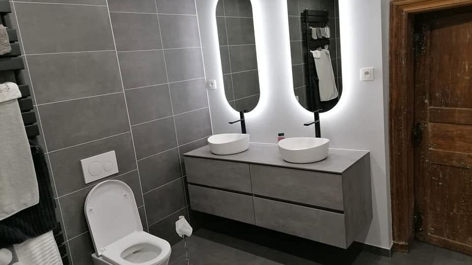 Salle de bain terminée : meuble suspendu à double vasque, miroirs rétroéclairés, WC suspendu et carrelage grand format