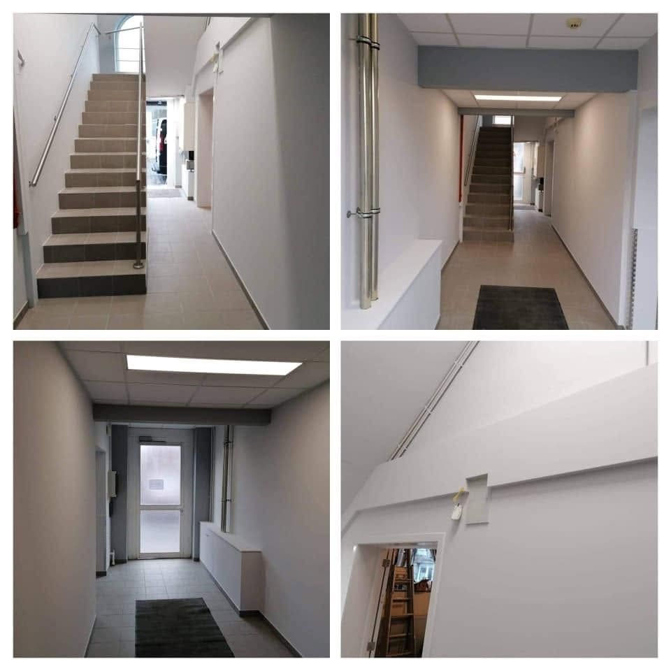 Hall et cage d'escalier d'immeuble après travaux : murs et plafonds peints, faux plafond avec éclairage, main courante et sol carrelé neufs