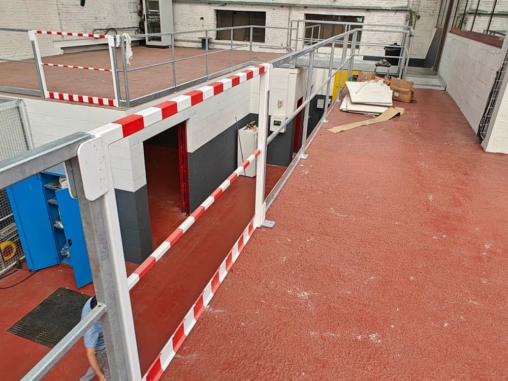 Garde-corps métallique posé en rive d'une plateforme, avec barrière de protection rouge et blanche au droit du vide