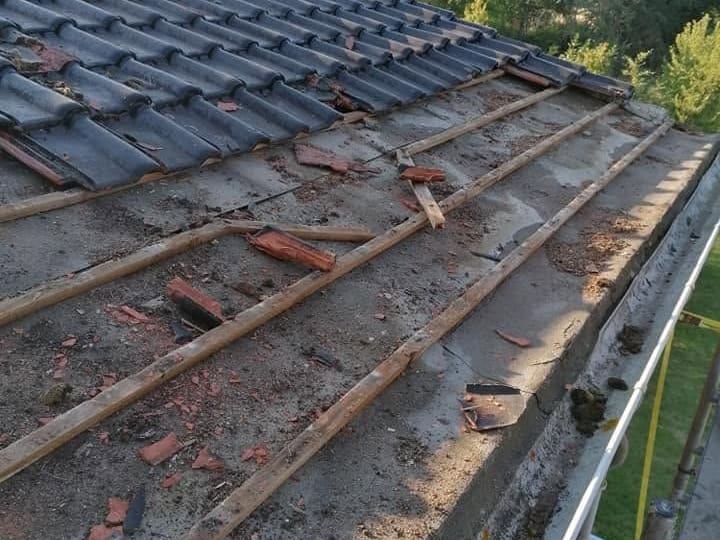 Dépose d'une couverture en tuiles : le versant est démonté rang par rang, laissant apparaître les liteaux et l'ancien support