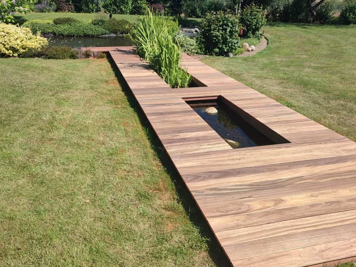 Platelage bois posé de plain-pied dans une pelouse, avec réservations pour un bassin et une plantation