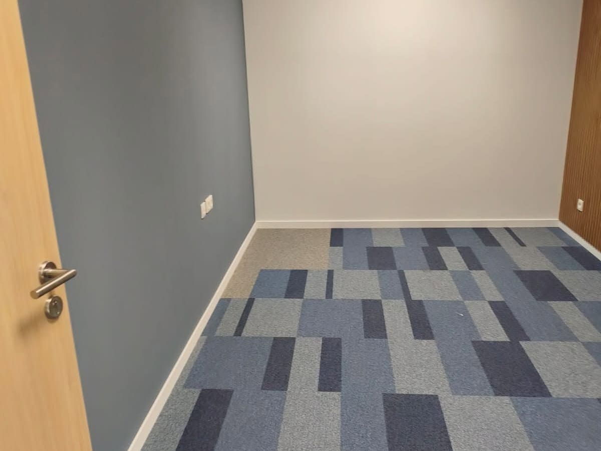 Bureau terminé : dalles de moquette bleues posées au sol, mur d'accent gris ardoise et faux plafond à dalles