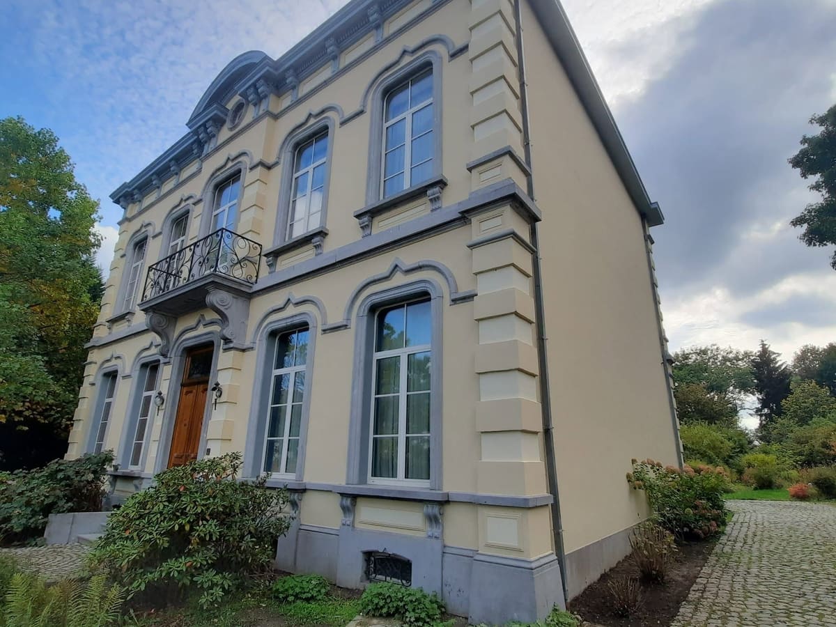 Façade de maison de maître remise en peinture : enduit crème, encadrements et chaînages d'angle repris en gris, soubassement en pierre bleue