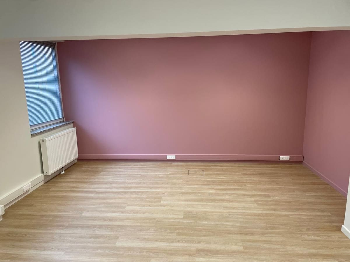 Pièce repeinte avec un mur en vieux rose et des plafonds blancs, plinthes assorties et sol stratifié clair