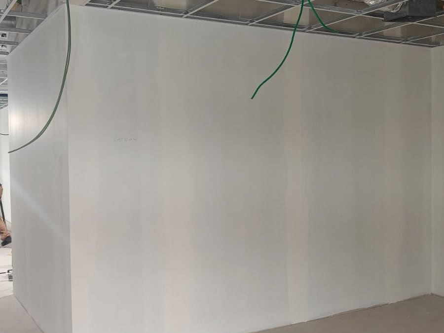 Cloison montée et jointoyée jusqu'à la retombée, ossature de faux plafond en place sous les gaines techniques apparentes