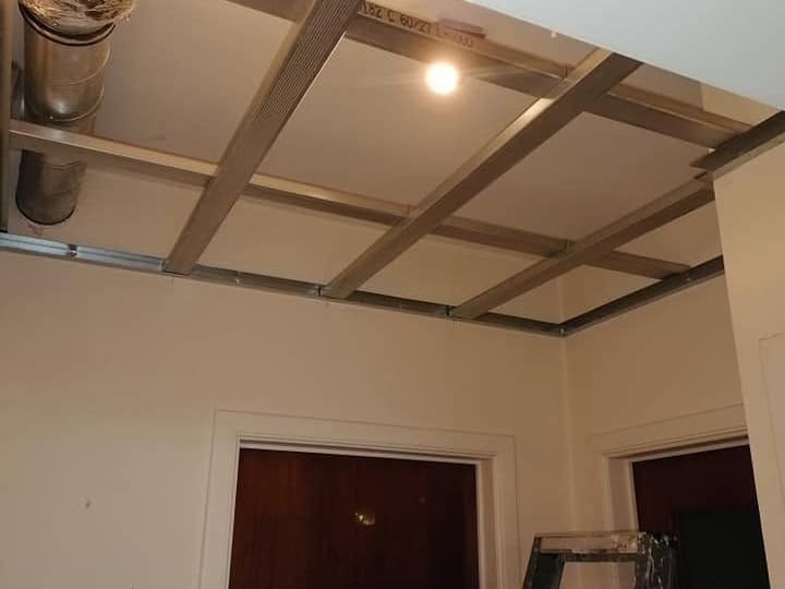 Ossature de faux plafond posée en trame régulière, suspentes réglées et gaines de ventilation passées au-dessus