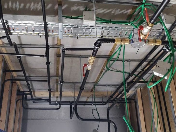 Attentes de plomberie et d'électricité posées dans une ossature de cloison avant fermeture : alimentations, évacuations et vanne d'arrêt
