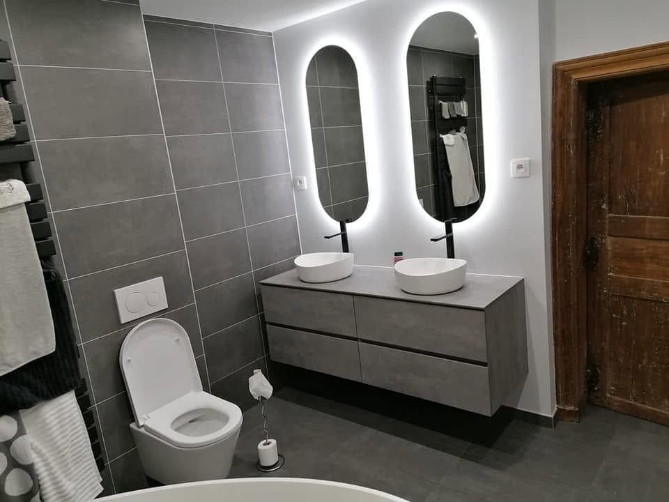 Salle de bain terminée : meuble suspendu à double vasque, miroirs rétroéclairés, WC suspendu et carrelage grand format